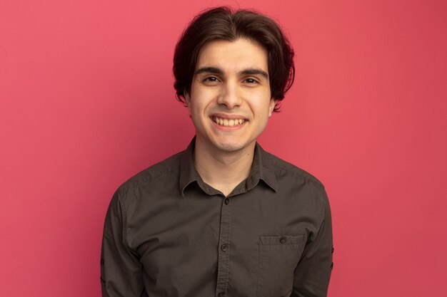 Chico guapo joven sonriente con camiseta negra aislada en la pared rosa