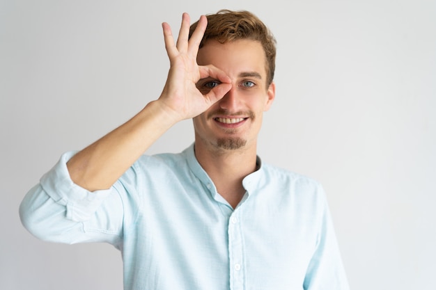 Foto gratuita chico guapo sonriente alegre imitando binoculares.