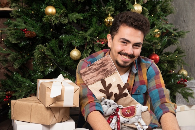 Chico guapo sonriente con cajas de regalo de Navidad.