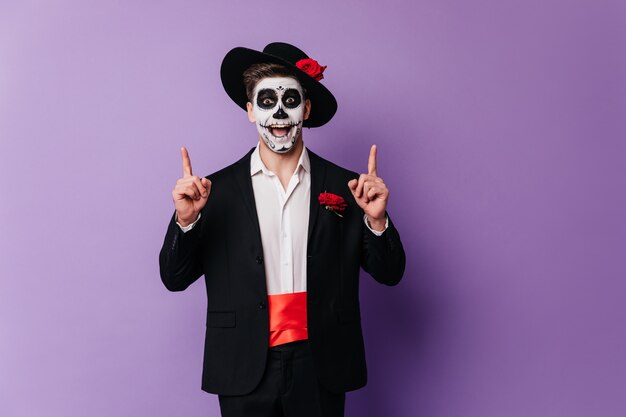 Chico guapo sorprendido en traje mexicano escalofriante en la fiesta. Foto de Halloween del hombre emocional en traje de zombie.