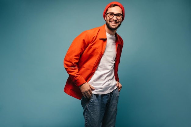 Chico guapo vestido con chaqueta brillante y jeans mira a la cámara