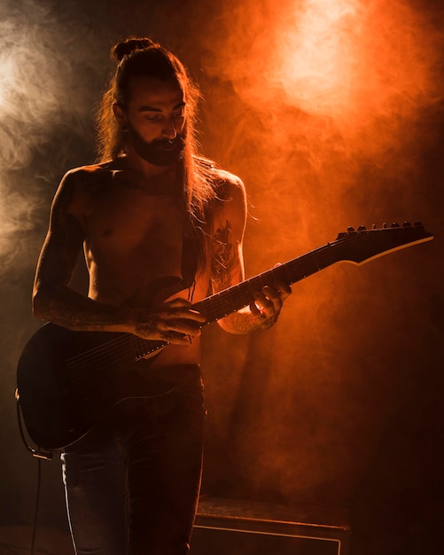 Chico de guitarra de pelo largo tocando acordes