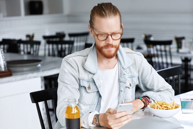 Chico hipster de moda vestido con camisa vaquera y gafas con estilo