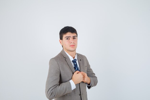 Chico joven apretando los puños sobre el pecho en traje formal