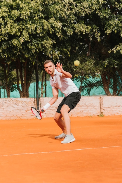 Chico joven atlético jugando al tenis