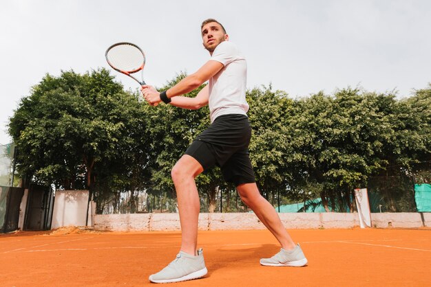 Chico joven atlético jugando al tenis