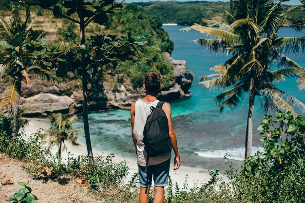 chico joven con barba y una mochila posando en la selva con una gorra