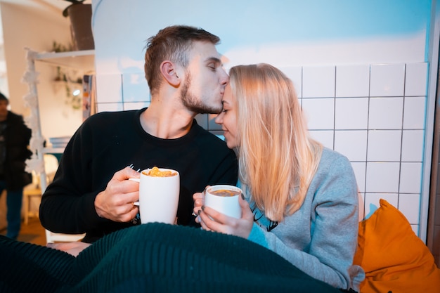 Chico con una joven bebiendo té y café caliente