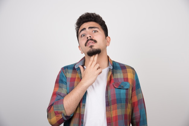 Chico joven confiado que gesticula el arma a la cabeza.