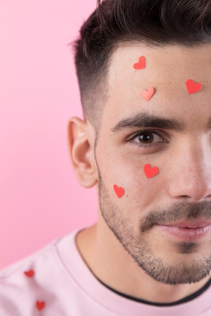 Foto gratuita chico joven con corazones de papel en la cara