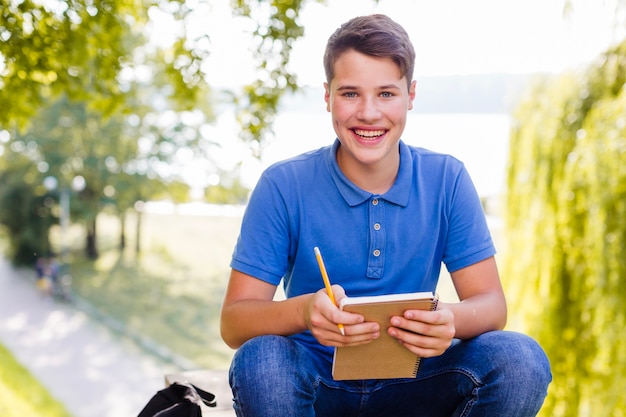 Chico joven con el cuaderno en el parque