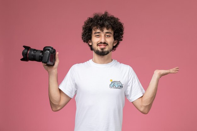 chico joven dando pose con la mano vacía y la cámara fotográfica