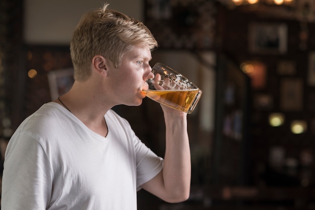 Chico joven disfrutando de cerveza en pub