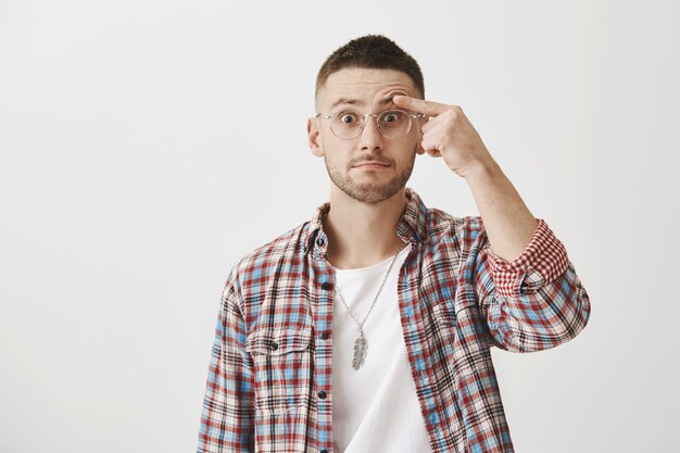 Chico joven divertido sorprendido con gafas posando