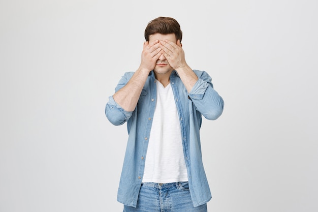 Chico joven guapo cerrar los ojos, de pie con los ojos vendados