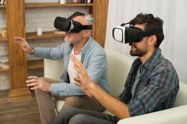 Chico joven y hombre de edad con gafas VR sentado en el sofá