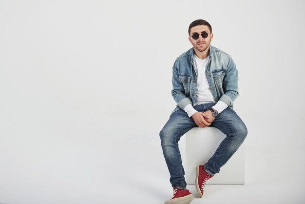 Chico joven inconformista con gafas riendo felizmente aislado en blanco