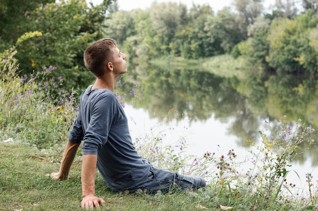 Chico joven mirando lejos al lado de un lago