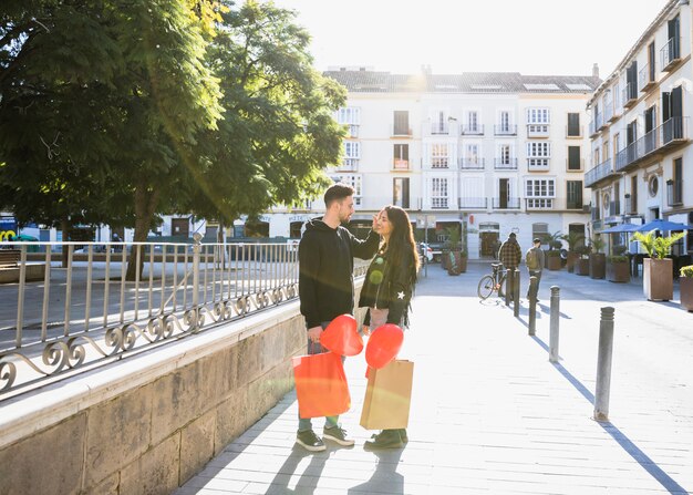 Chico joven con paquetes y globos cerca de Ady en la calle