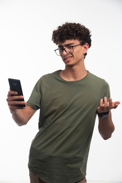 Chico joven con pelos rizados revisando mensajes incómodos.