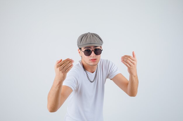 Chico joven que invita a entrar en camiseta, sombrero y que parece seguro de sí mismo. vista frontal.