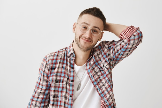 Chico joven sonriente guapo modesto con gafas posando