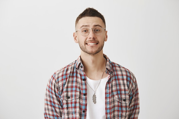 Foto gratuita chico joven sonriente incómodo con gafas posando