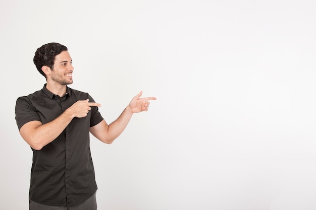 Foto gratuita chico joven sonriente señalando con espacio para copiar