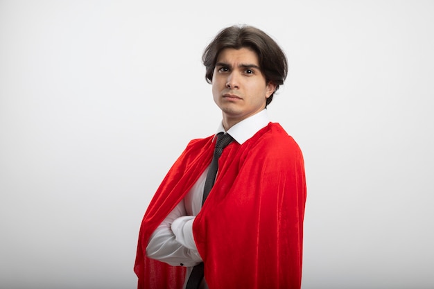 Foto gratuita chico joven superhéroe confiado mirando a la cámara con corbata cruzando las manos aisladas en blanco