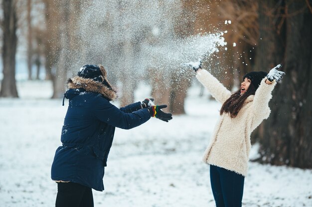 Chico juguetón lanzando nieve a su novia