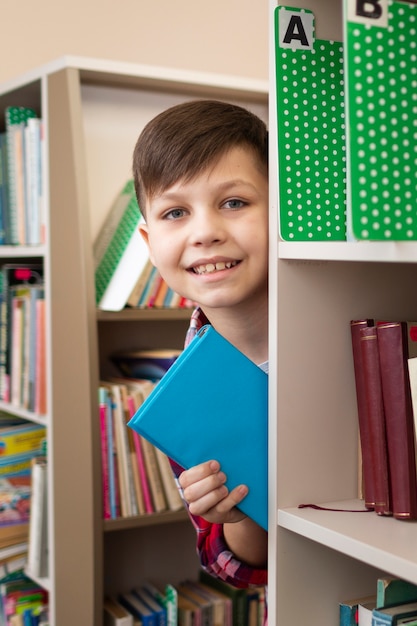 Foto gratuita chico con libro entre estantes