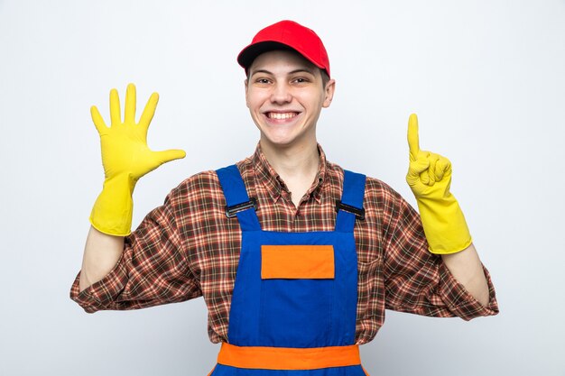 Chico de limpieza joven con uniforme y gorra con guantes aislado en la pared blanca