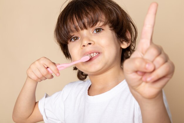 chico lindo adorable limpiando sus dientes en rosa
