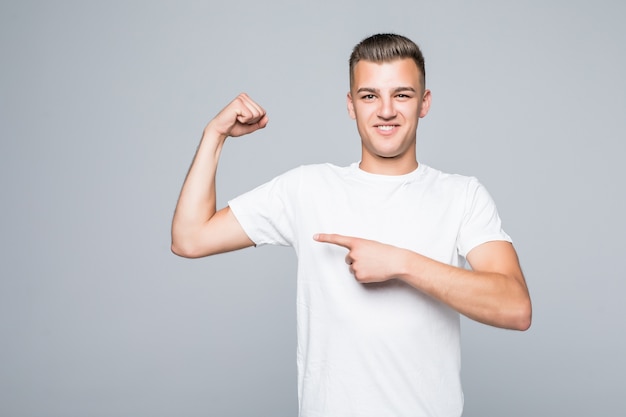 Chico lindo joven muestra su cuerpo musculoso aislado en la pared blanca