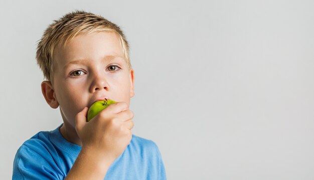 Chico lindo mordiendo una manzana verde