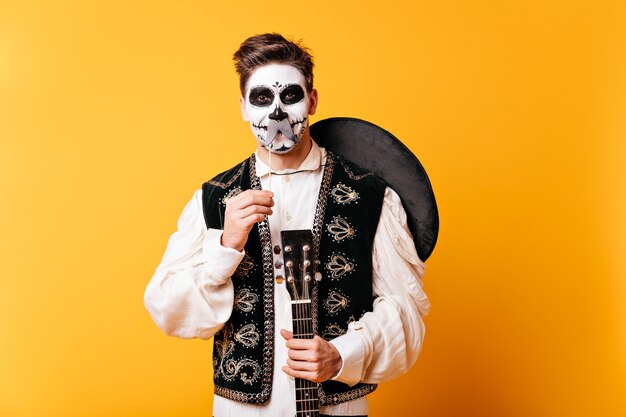 Chico con maquillaje para Halloween y sombrero a la espalda se divierte y posa con bigotes postizos.