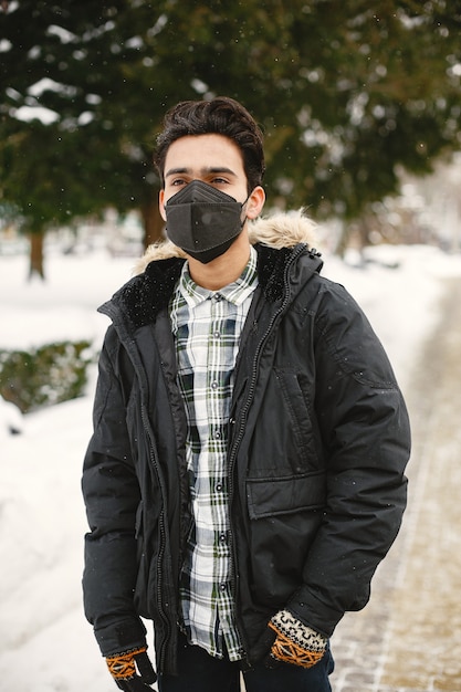 Foto gratuita chico con máscara. indio en ropa de abrigo. hombre en la calle en invierno.