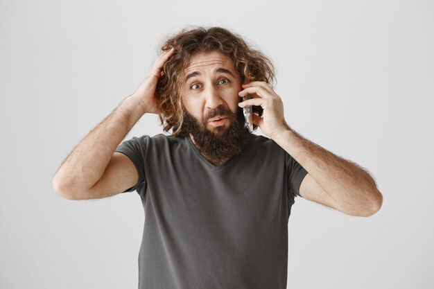 Chico del Medio Oriente confundido y vacilante hablando por teléfono y parece indeciso