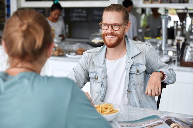 Chico de moda hipster sentado con una mujer en el café