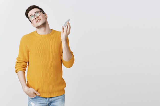 Foto gratuita chico molesto que desea finalizar la llamada, poner los ojos en blanco y retirar el teléfono móvil