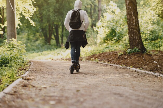 El chico monta un scooter eléctrico en el verano Pforest