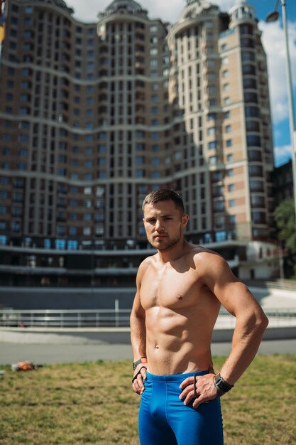 Chico musculoso posando al aire libre. Retrato de un hombre guapo con pantalones cortos azules.