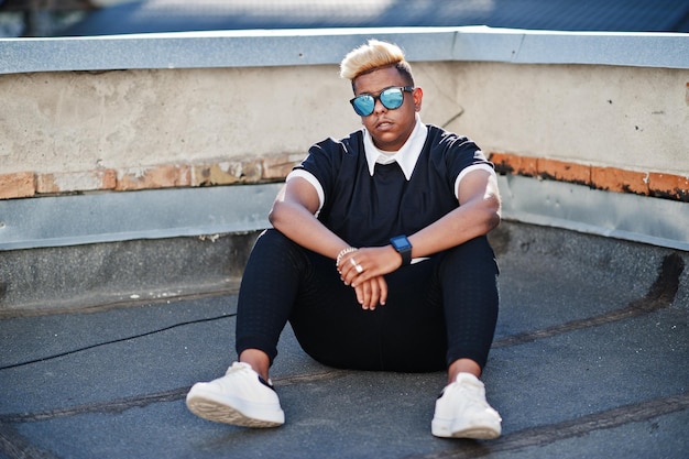 Foto gratuita chico musulmán árabe elegante con cabello original y gafas de sol posadas en las calles en el techo