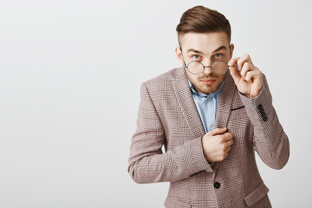 Chico nerd inseguro con gafas y traje que parece tímido y sospechoso