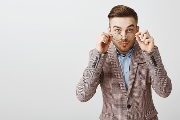 Chico nerd inseguro con gafas y traje que parece tímido y sospechoso