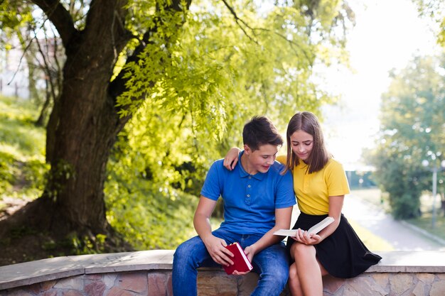 Chico con niña leyendo el libro en el parque