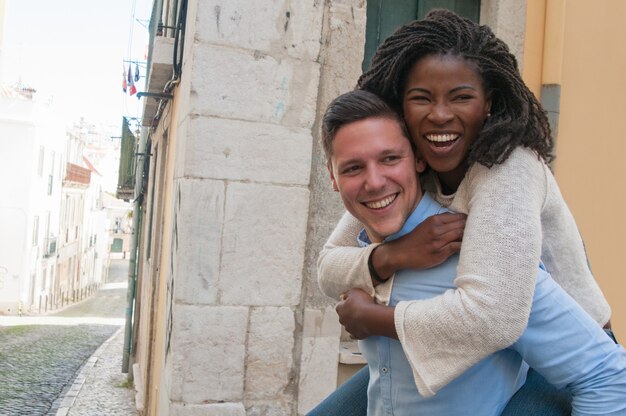 Chico con novia feliz en la espalda en la ciudad