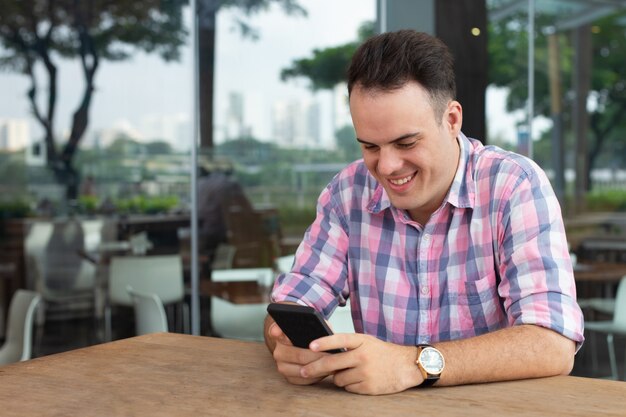 Chico optimista alegre utilizando nueva aplicación en smartphone