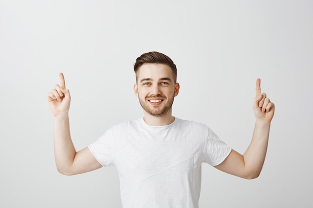 Chico orgulloso feliz sonriendo y señalando con el dedo hacia arriba