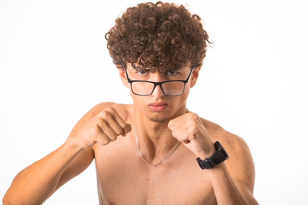 Chico de pelo rizado en gafas ópticas perforando con las dos manos.